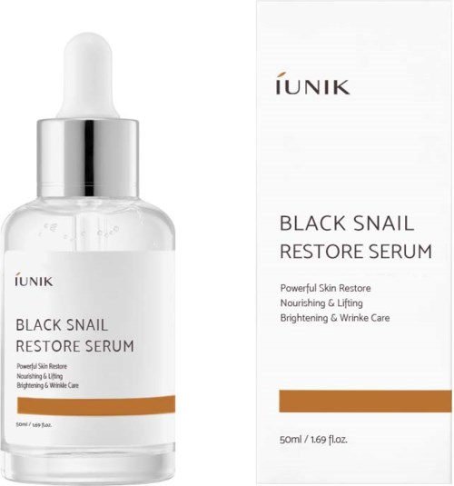 En klar glasflaska med dropper innehåller Black Snail Restore Serum, bredvid dess vita förpackning med produktinformation.