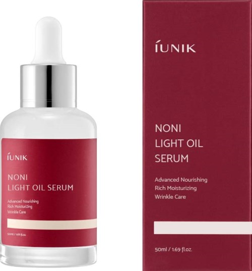 En vit flaska med droppkork och röd etikett, bredvid en matchande röd box, båda för hudvårdssserum.