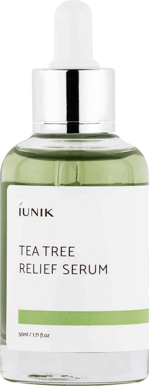 En liten grønn flaske med dråpeteller, merket 'IUNIK TEA TREE RELIEF SERUM', på hvit bakgrunn.