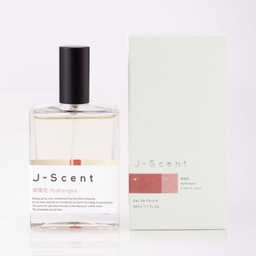Ein Parfümflasche mit schwarzem Verschluss neben einer weißen Box mit rosa und grauen Labels zeigt J-scent Hydrangea Eau De Parfum.