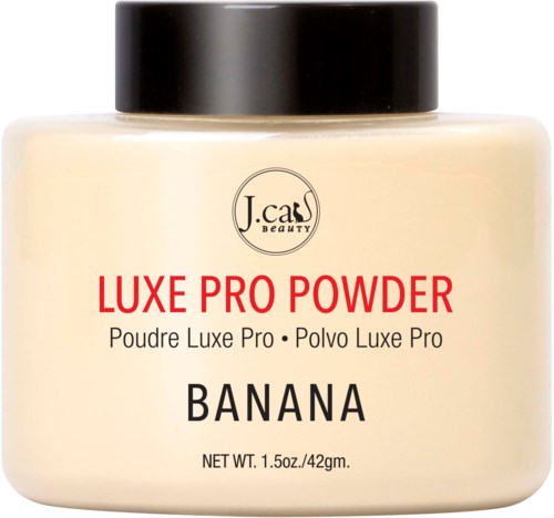 Et cremefarvet glas med sort låg viser J.cass Beauty Luxe Pro Powder i bananskygge.