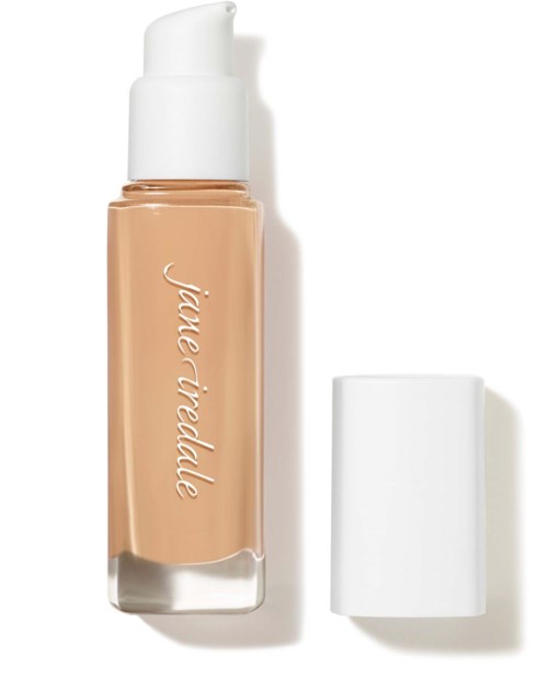 A bottle of liquid foundation with a white pump and a separate white cap. The bottle has a beige liquid inside.