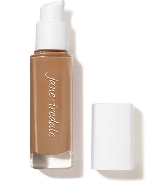 En beige flytande foundationflaska med vit kapsyl och etikett, med kapsylen bredvid.