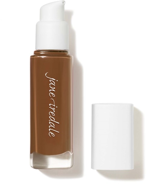 A brown liquid foundation bottle with a white pump and a white cap nearby.