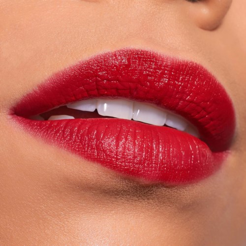 Close-up van lippen met felroze lippenstift en een deel van de tanden zichtbaar.
