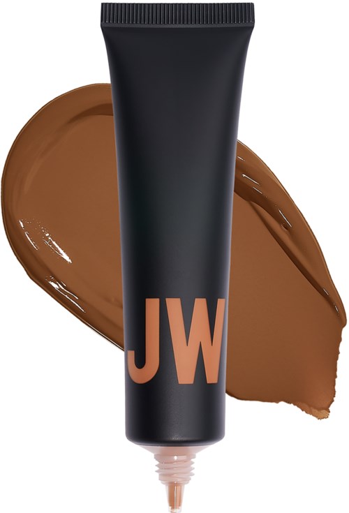 En svart tube med 'JW'-logo, med brunt kremspredning bak den, ser ut som makeup eller foundation.