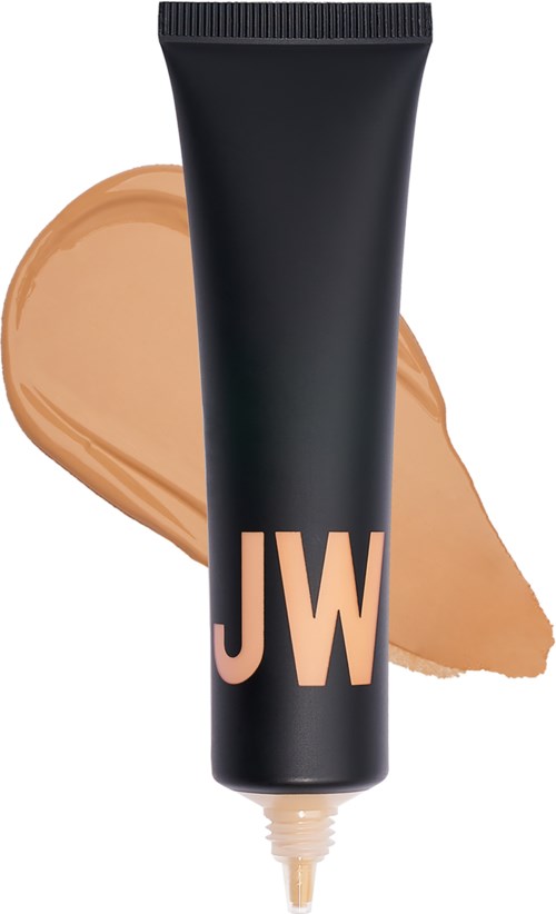 En svart tube med beige bokstaver 'JW' og beige foundation spredd bak den.