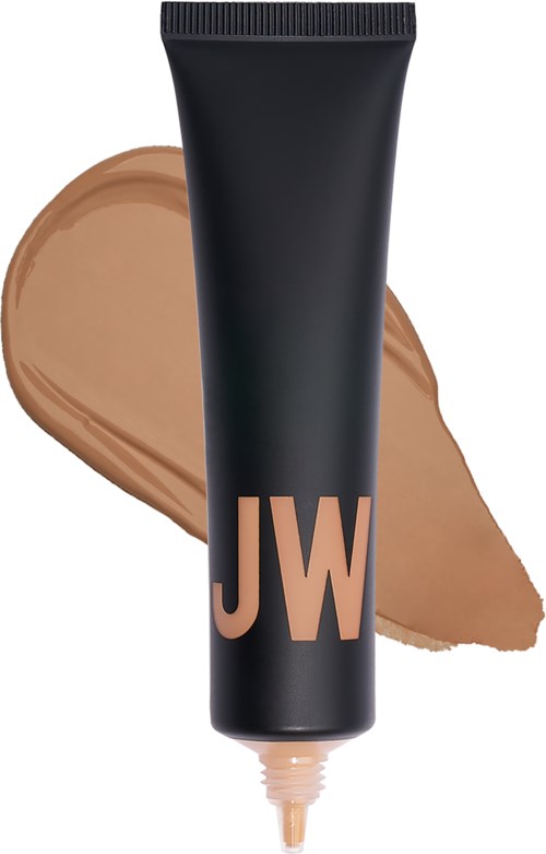 En svart tube merket 'JW' med beige sminke eller foundation ved siden av.