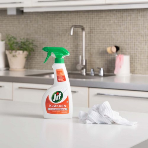 En flaske med kjøkkenspray og en klut på en ren hvit kjøkkenbenk.