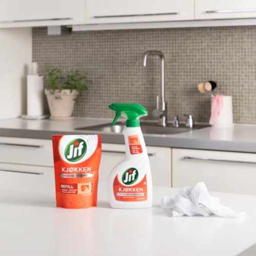 Rengjøringsspray, refill-pose og klut på et kjøkkenbord.