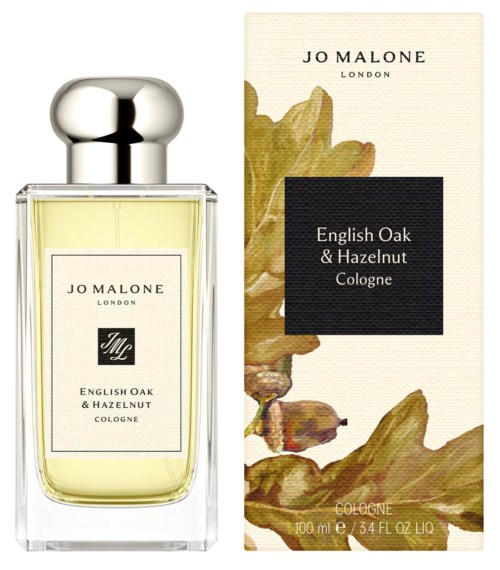 A perfume bottle with a silver cap and light yellow liquid, alongside a box with leaf illustrations and text.