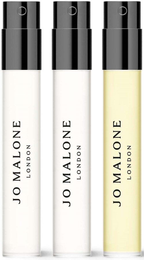 Drie kleine flesjes met zwarte doppen, gemarkeerd als Jo Malone London, bevatten verschillende geuren of producten.