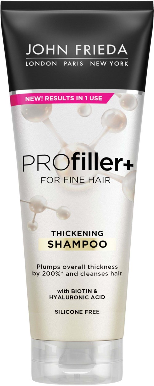 A shampoo bottle with black top, white body, pink label, and text about hair thickening and ingredients.