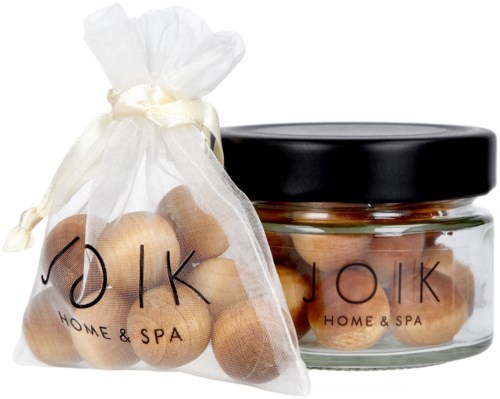 Et glasglas og en stofpose indeholder små træbolde til hjemmets spa, mærket 'JÖIK HOME & SPA' på begge.