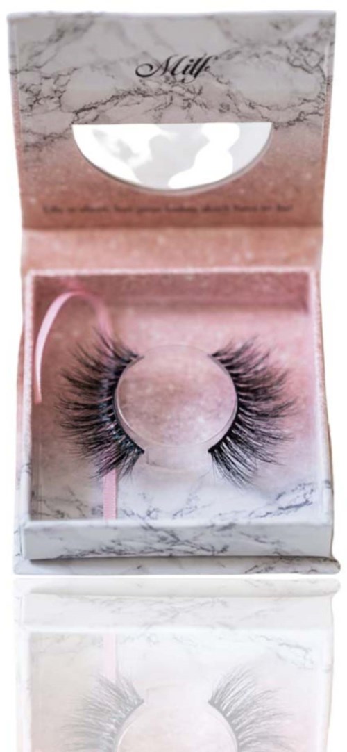 A box with pink and white marble design contains false eyelashes on a pink stand.
