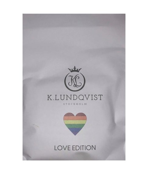 En vit väska med en svart krona logga, regnbågsfärgat hjärta och text om Love Edition från K. Klundovist, Stockholm.