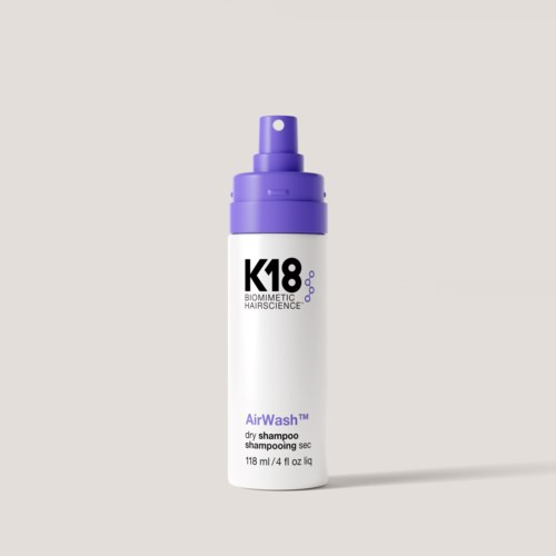 Eine weiße Flasche mit lila Deckel, beschriftet mit K18 Biometric Hairscience und AirWah Trockenshampoo.