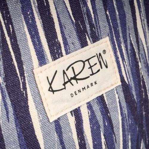 Ein Kleidungsetikett zeigt den Markennamen 'KAREN' und 'DENMARK' auf Stoff mit blauen und weißen Streifen.