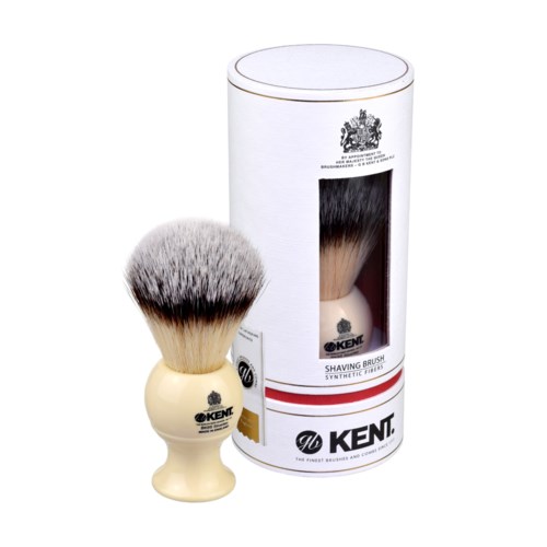 A shaving brush with a cream-colored handle and thick, soft bristles, in front of its cylindrical box packaging.