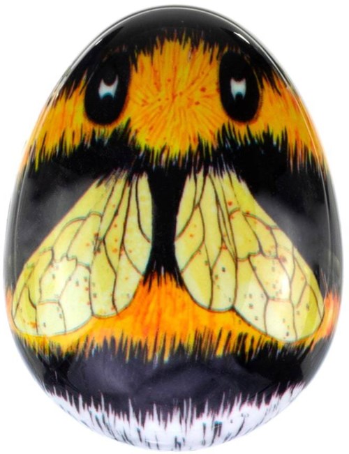 Ein bemaltes Ei mit einem Schmetterlingsgesicht und Flügeln, in leuchtendem Orange, Schwarz, Gelb und Weiß.