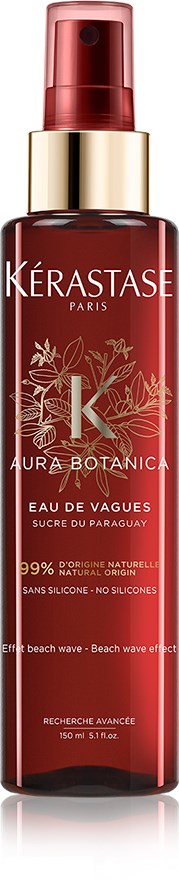 En rød sprayflaske med guld accenter, mærket Kérastase, Aura Botanic, Eau de Vagues, med botaniske illustrationer.