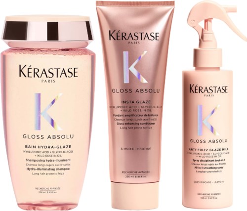 Kolme Kérastase-hiustuotetta vaaleanpunaisissa pulloissa: shampoo, hoitoaine ja suihke.