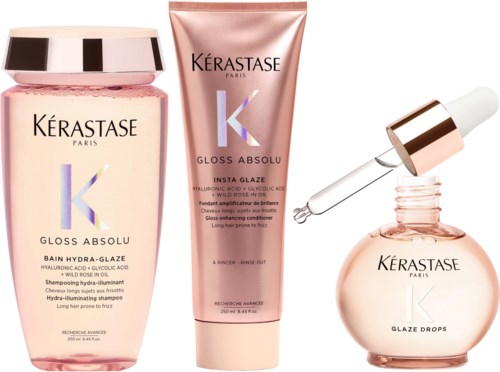 Tre Kérastase hårpleieprodukter: sjampo, hårmaske og serum, i rosa og roségull emballasje.