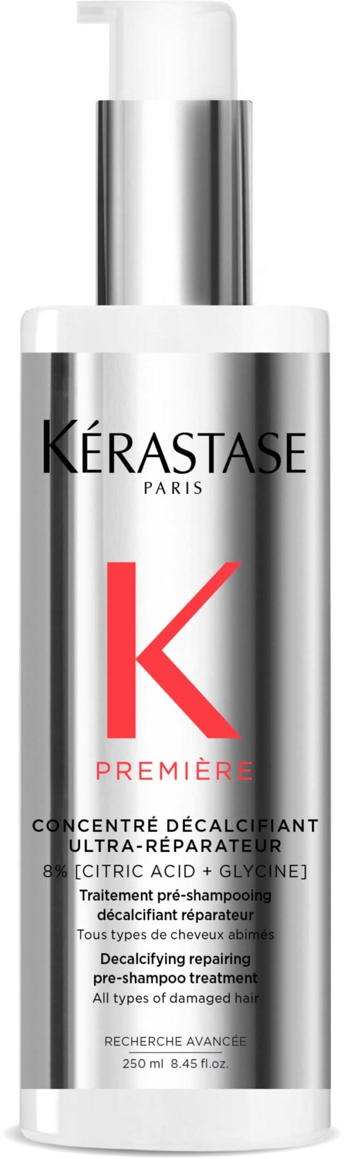 En lang, sølvfarvet flaske med pumpe, mærket Kérastase Paris, indeholder en afkalkende, reparerende hårbehandling med rød og sort tekst.
