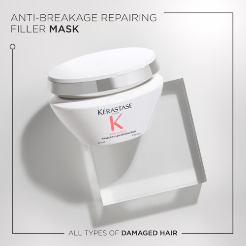 Dette er en hvid krukke med hårmaske til beskadiget hår, mærket Kerastase, med en sølvtop, på en udstillingsstand.