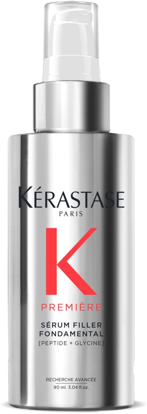 En silverfärgad flaska med pump, märkt Kérastase Paris, innehållande ett serum för hud eller hår. Röd bokstav K och text.