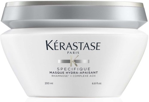 A white jar with a silver lid contains hair mask from Kerastase Paris, labeled for soothing and hydrating hair care.