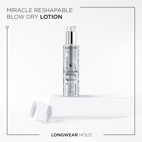 En tydlig flaska med blow dry-lotion med pump, märkt 'Kerastase', står på en vit yta med ett lock nära.