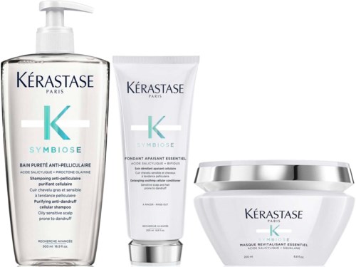 Three hair care products from Kérastase: shampoo, conditioner, and mask, in white containers with blue and black text.