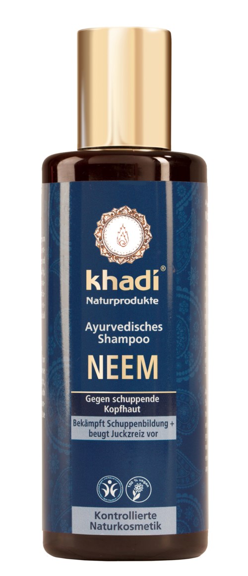 En flaske med Khadi Neem sjampo med blå og gull etikett, som påstår å forhindre flass og styrke håret.