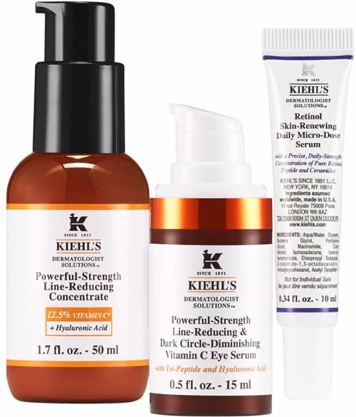 Drie huidverzorgingsflessen in verschillende maten bevatten verschillende serums voor huidverzorging. Labels tonen ingrediënten en doel.