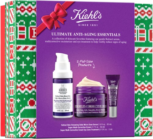 Ett Kiehl's hudvårdsset med lila behållare, en röd rosett och en julinspirerad grönt, rött och vitt bordermönster.