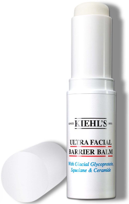 En hvit tube av Kiehl's Ultra Facial Barrier Balm med hvit lokk og etikettdetaljer. En rund hvit svamp er i nærheten.