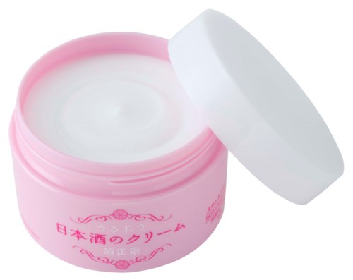 A pink jar with Japanese writing and a white lid, open to reveal white cream inside.