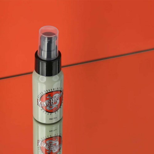 A spray bottle with a 'King BBQ' label stands on a red surface. It likely contains a sauce or marinade.