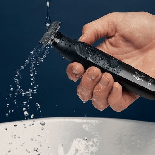 En persons hand håller en svart rakhyvel under rinnande vatten för att rengöra den.