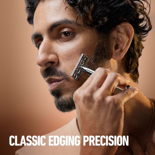 A man with dark hair shaves his beard with a safety razor. Text says 'Classic Edging Precision'.