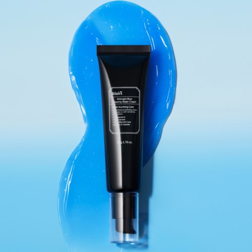 A black tube of moisturizer cream placed on a blue surface with water splashes around it.