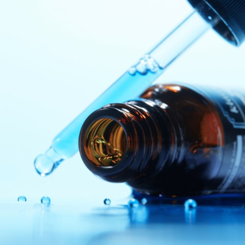 Eine dunkelbraune Glasflasche mit Pipette, die eine Wassertropfen abgibt, umgeben von blauen Tropfen.