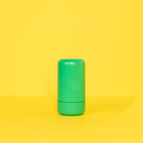 En liten grønn deostick med lokk, mot en gul bakgrunn.
