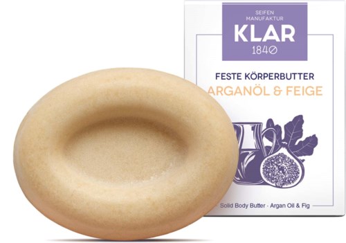 En tvål i ringform framför en etikett för kroppssmörj med fikon och arganolja.