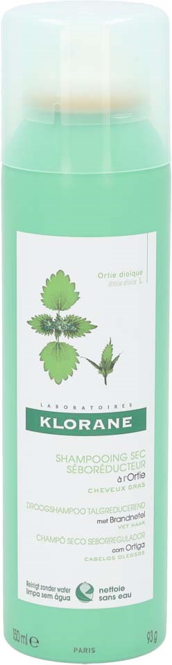 A green bottle of Klorane shampoo with images of herbs on the label.