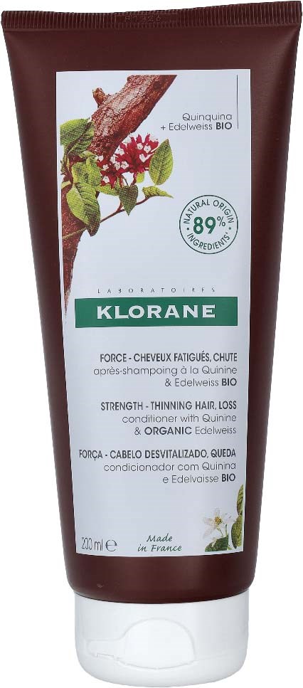 Green and white label on a brown tube of hair conditioner with plant illustrations and text about organic ingredients.