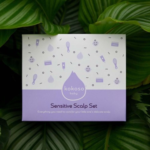 Eine Box mit der Beschriftung 'Sensitive Scalp Set' und Illustrationen von Haarpflegeprodukten, auf grünen Blättern.