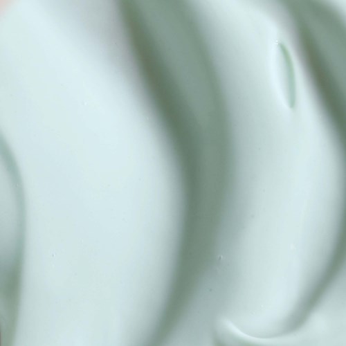 A close-up of a light green, smooth, wavy surface with a small hole or indentation.