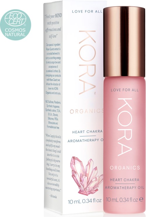 En rosa flaska KORA Organics Heart Chakra Aromatherapy Oil med en rosenkvarts illustration och en box bredvid.